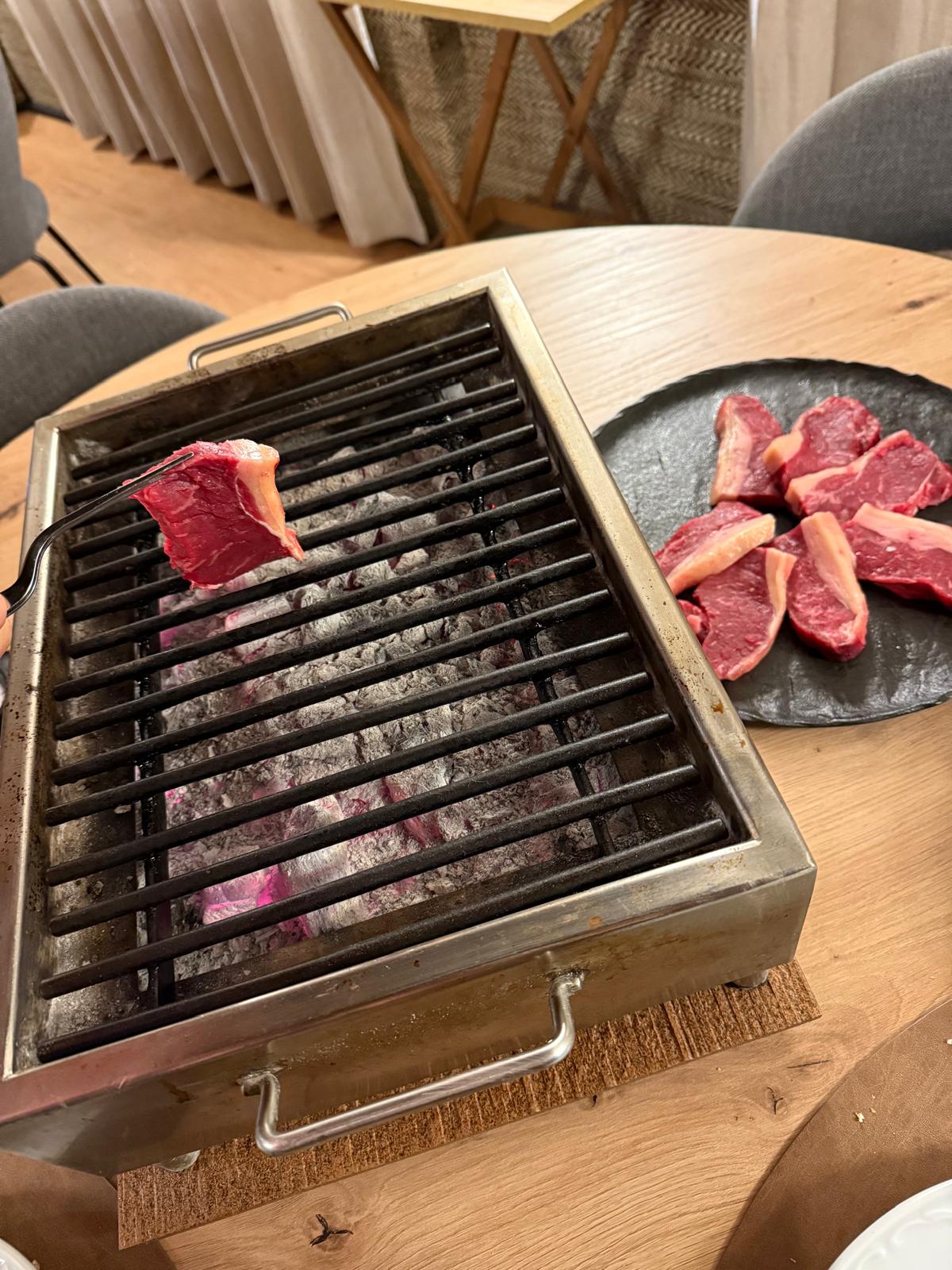 Carne asándose a la parrilla con brasas