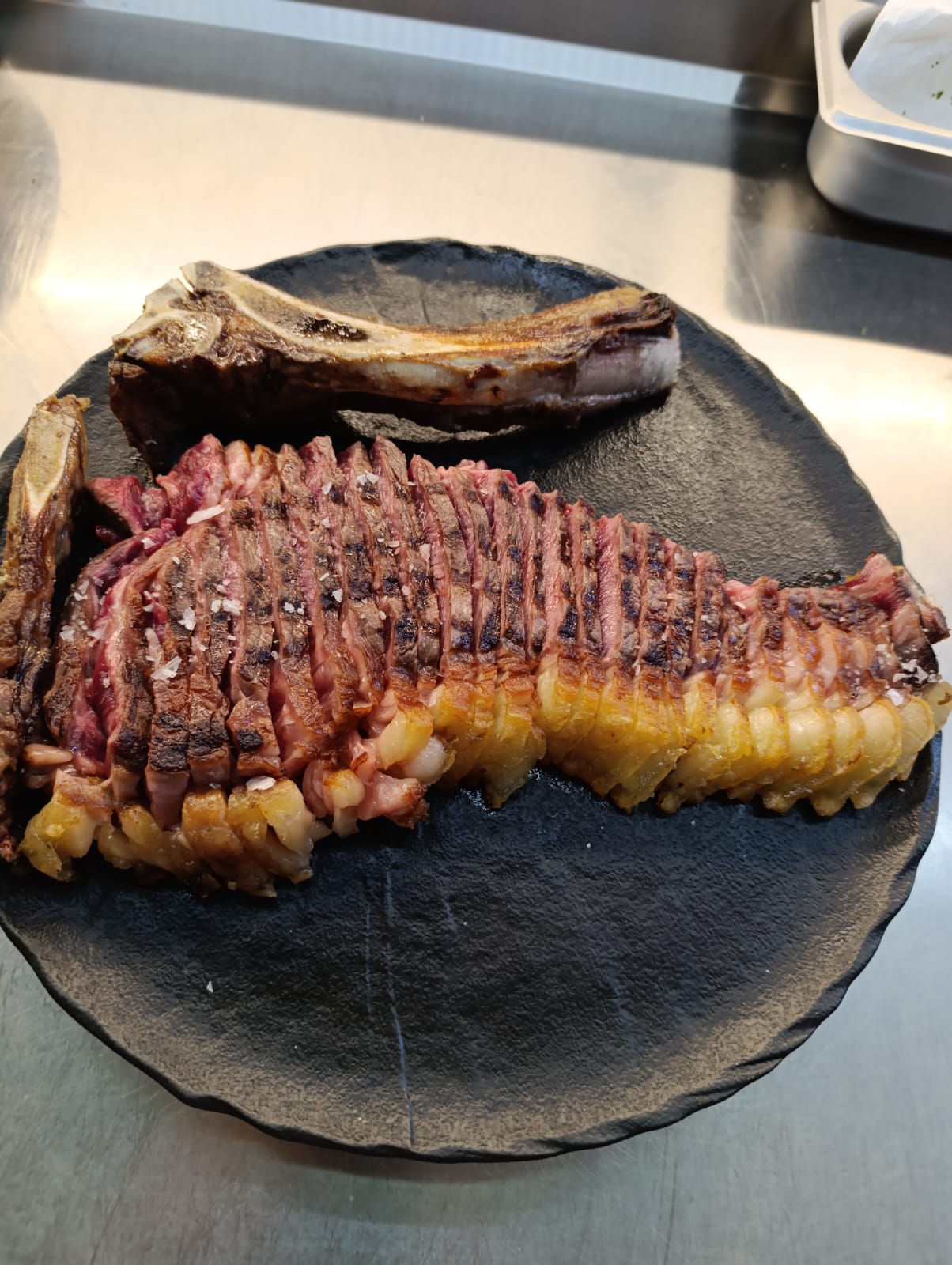 Chuletón cortado con sal sobre plato negro