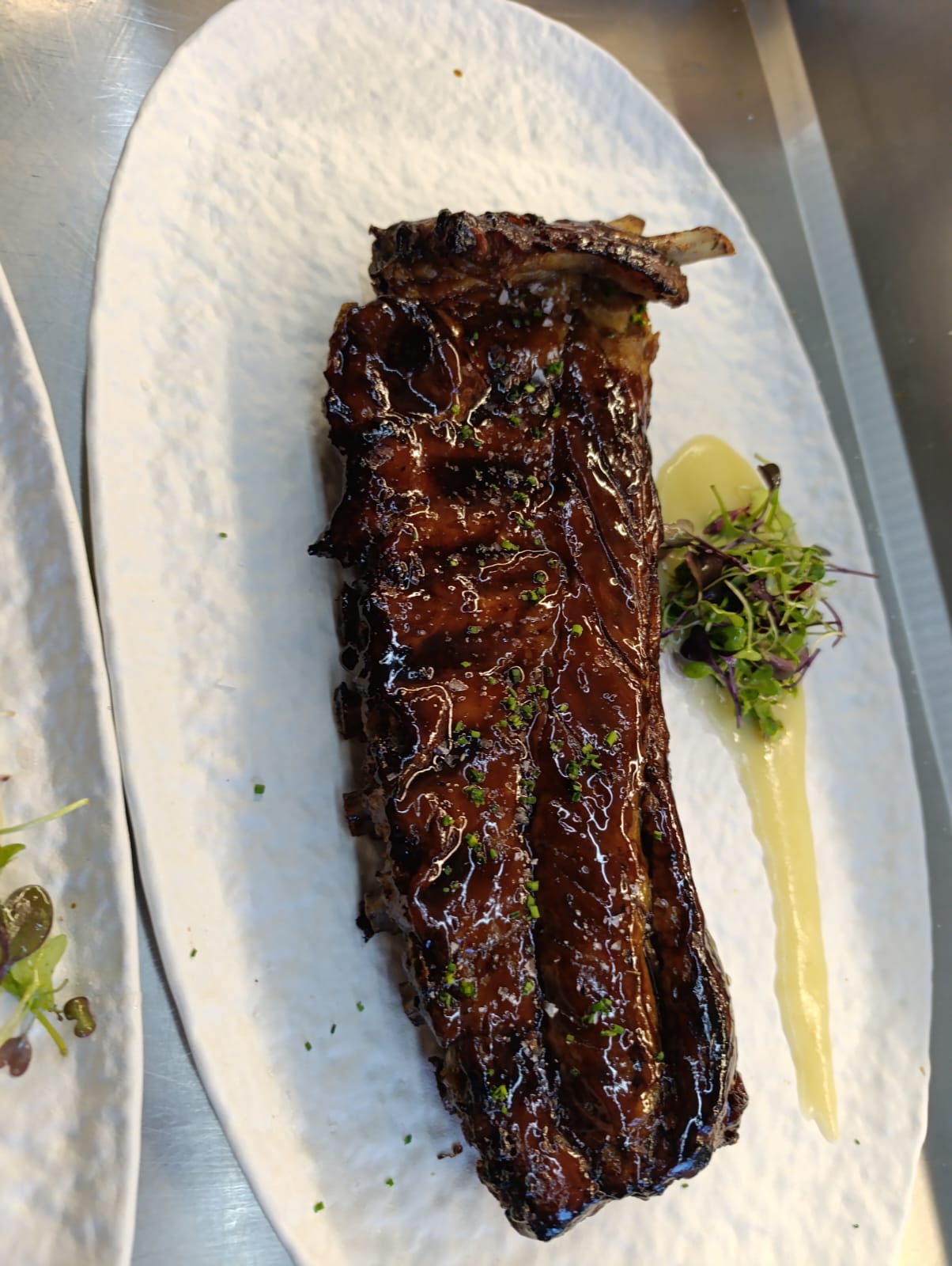 Costillar glaseado y brillante servido en plato blanco